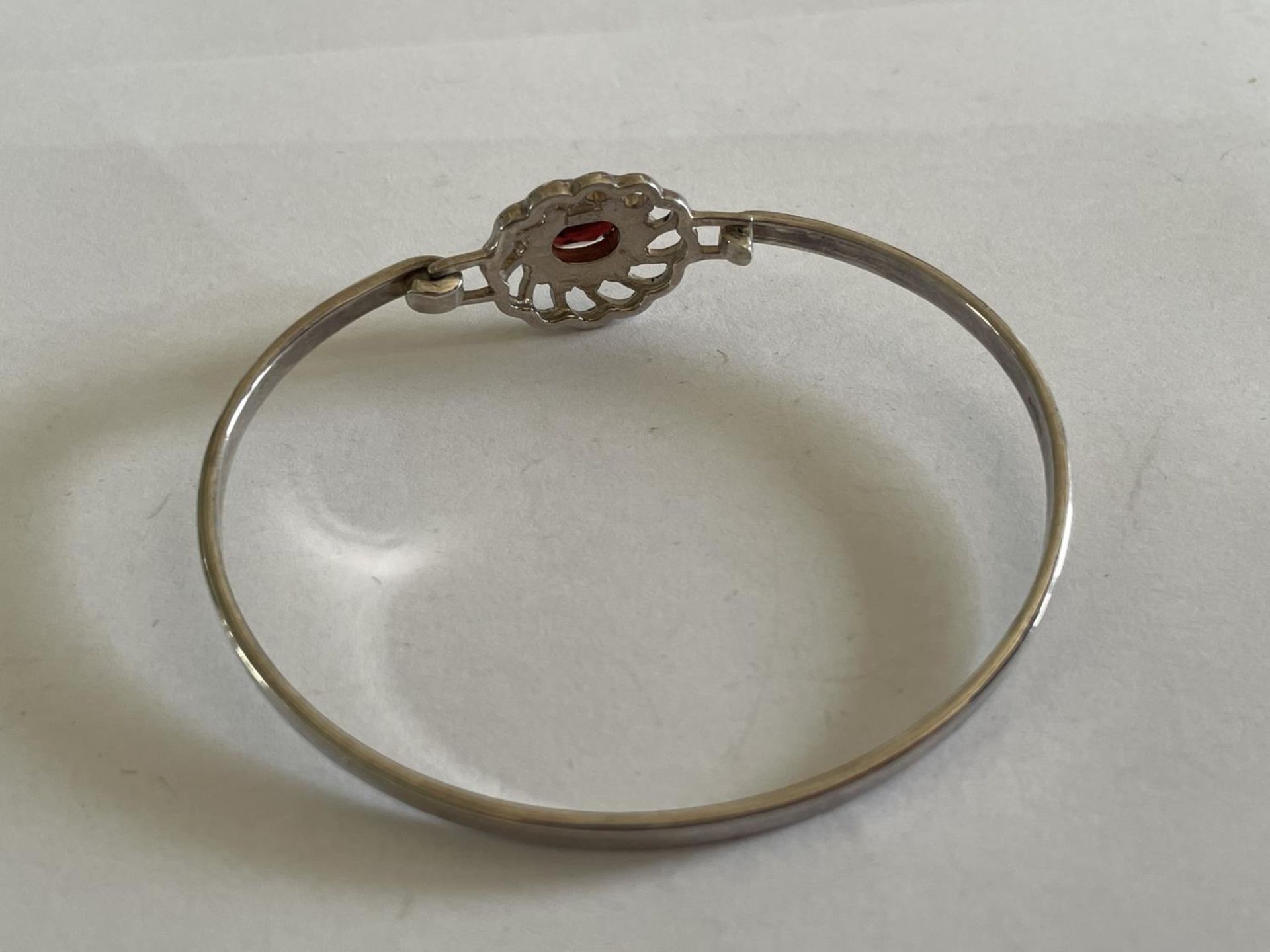 A SILVER BANGLE WITH RED STONE - Image 2 of 3