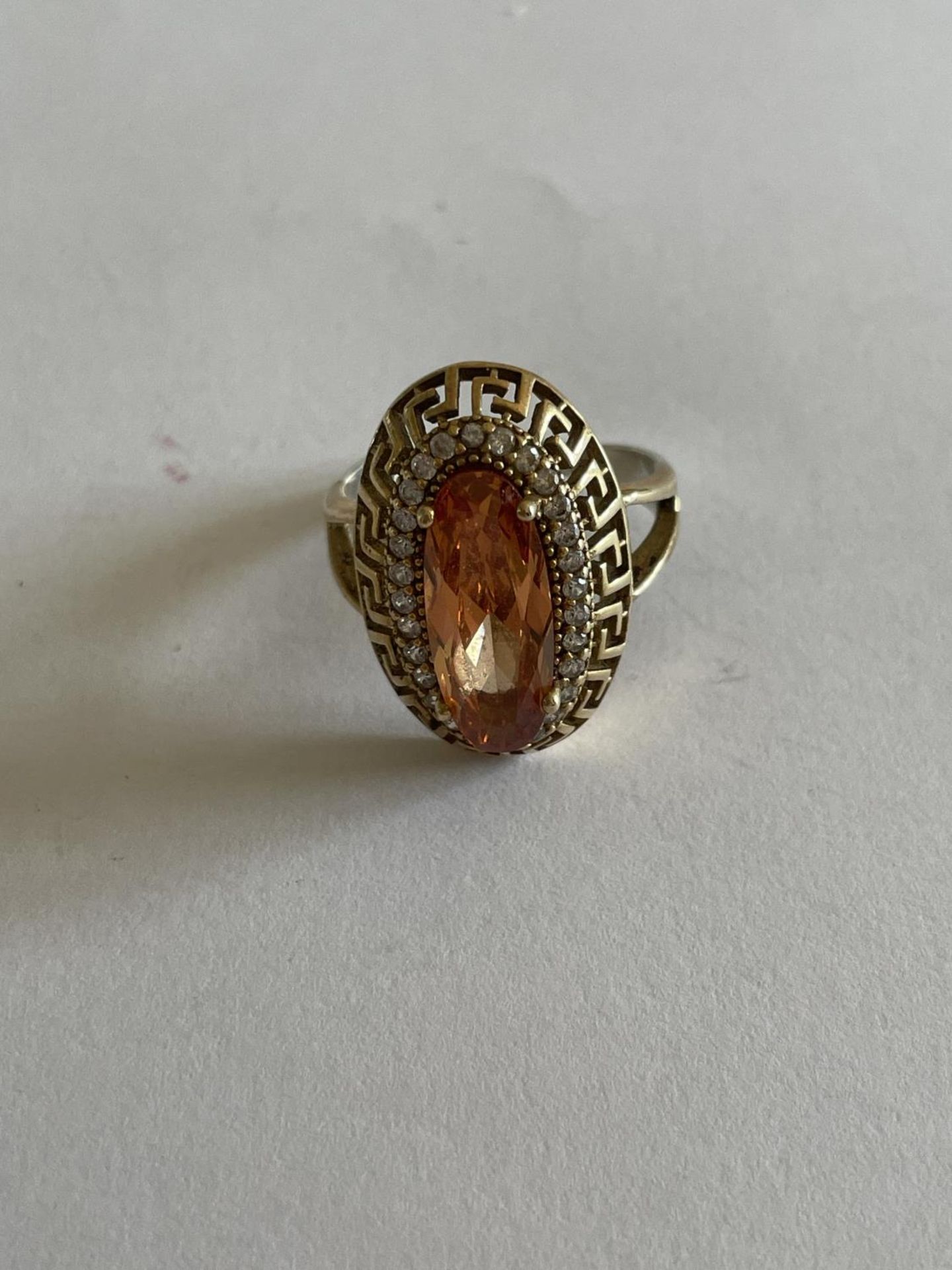 A DECORATIVE SILVER AND GOLD RING WITH LARGE AMBER COLOURED STONE SURROUNDED BY CLEAR STONES SIZE