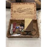 A CIGAR BOX CONTAINING VINTAGE PENKNIVES, RED CROSS BADGES, A BOTTLE STOPPER WITH WHITE METAL DUCK