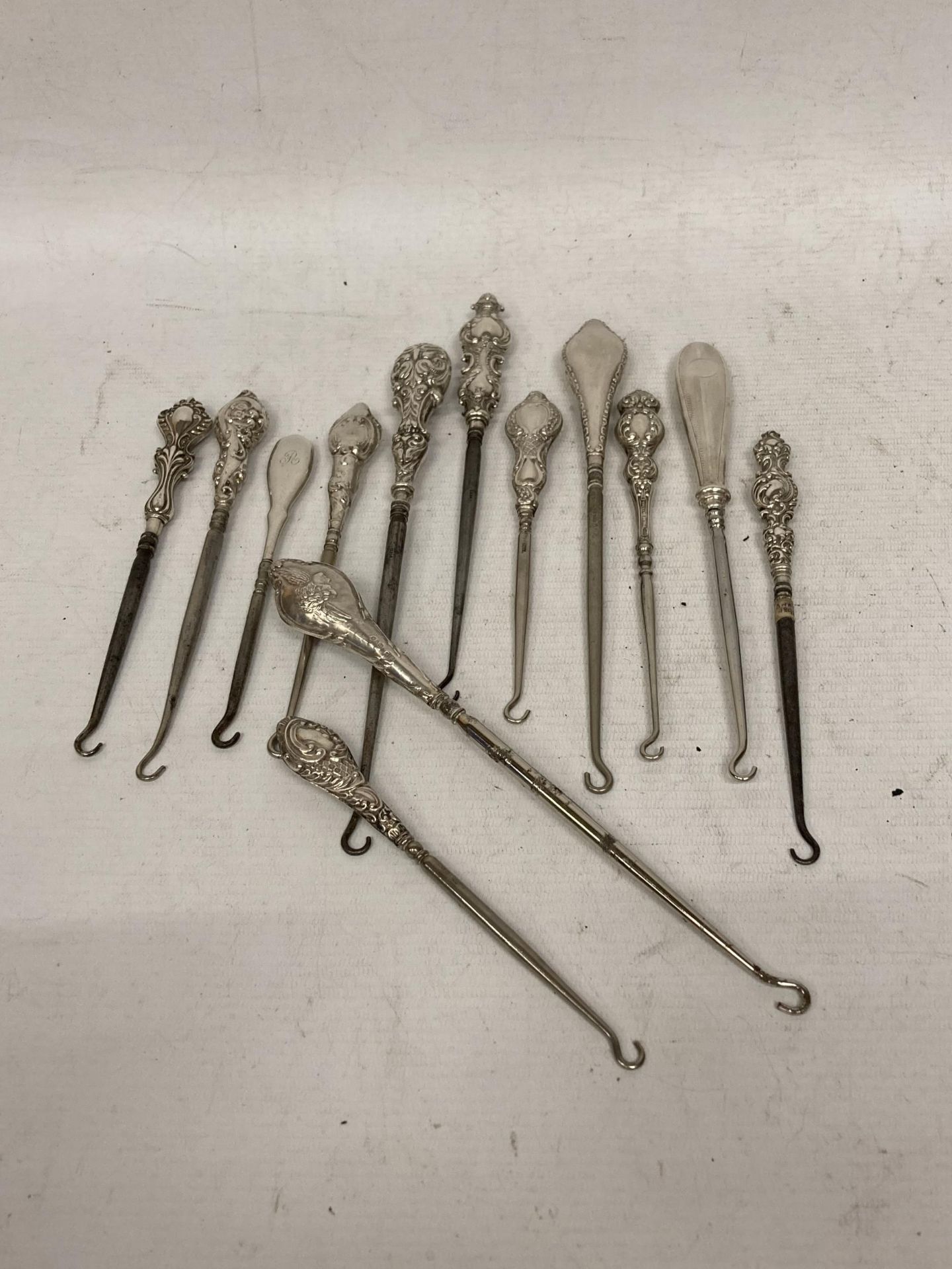 A COLLECTION OF THIRTEEN VICTORIAN AND LATER SILVER HANDLED BUTTON HOOKS