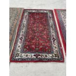 A SMALL RED PATTERNED FRINGED RUG