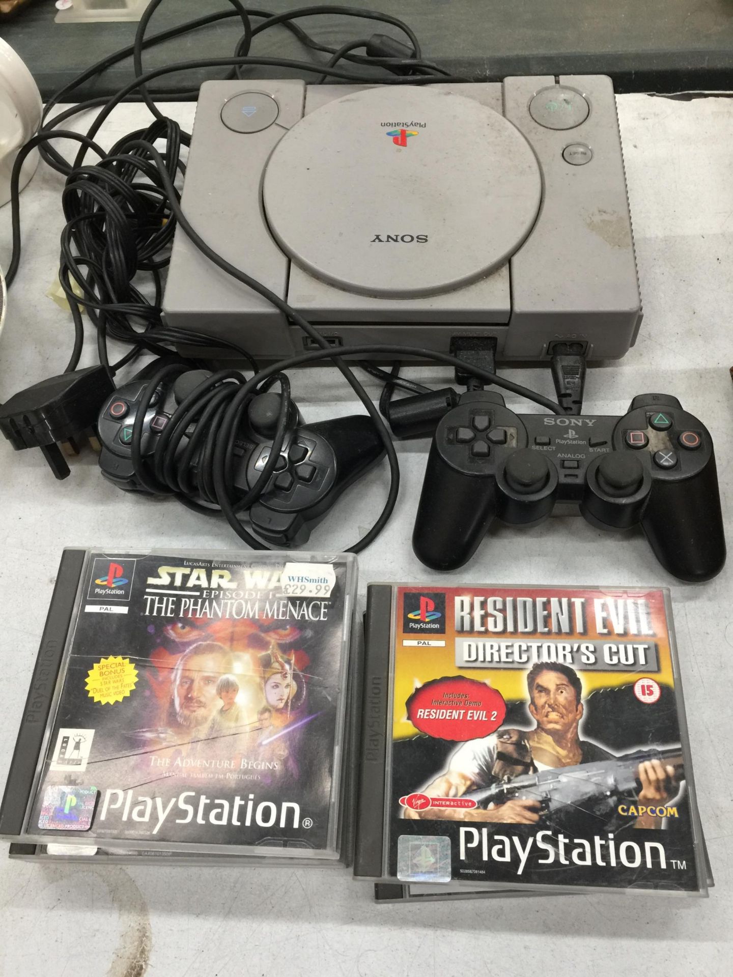 A SONY PLAYSTATION ONE WITH TWO CONTROLLERS AND FIVE GAMES TO INCLUDE STAR WARS THE PHANTOM