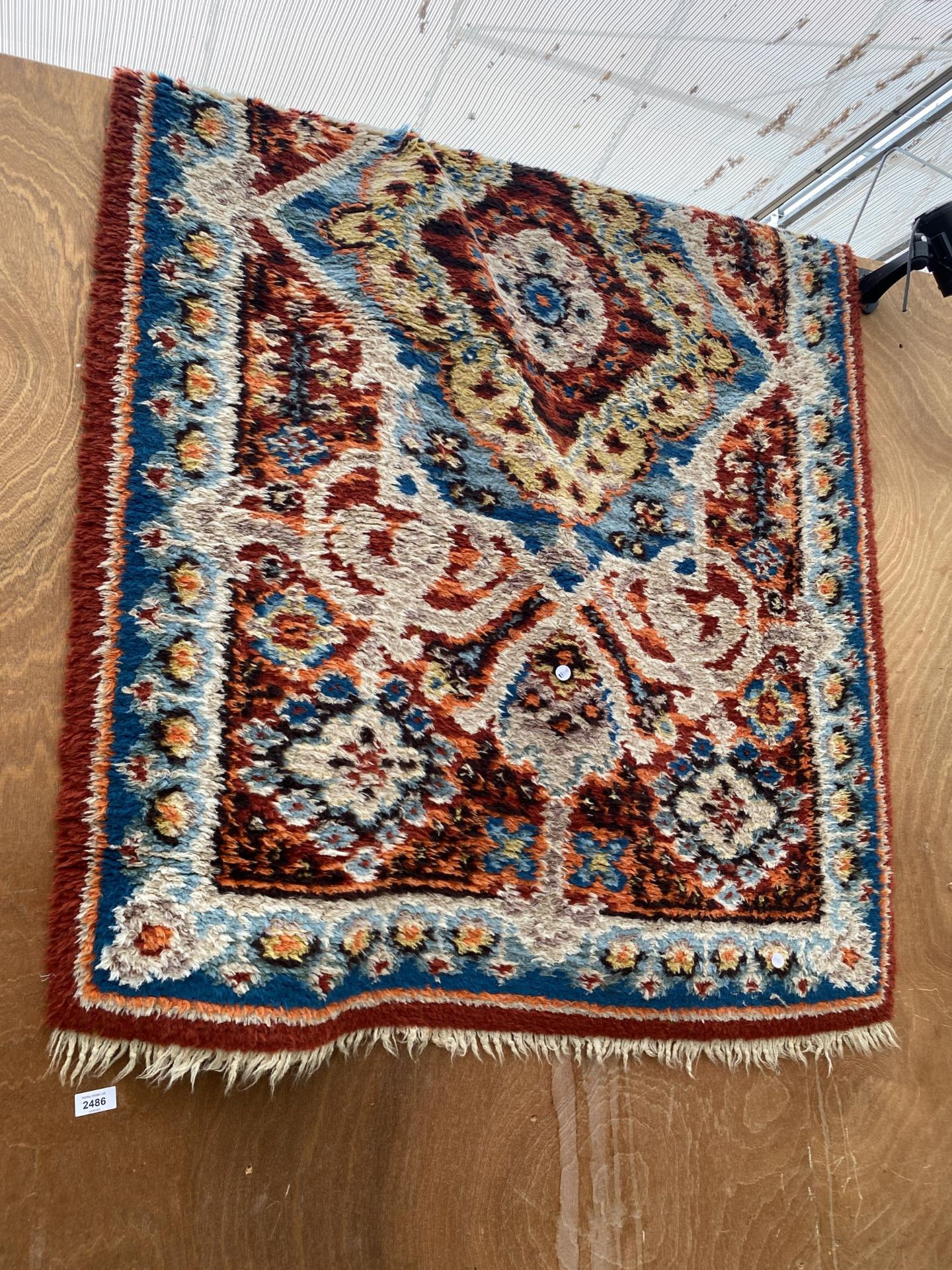 A MULTI COULOURED PATTERNED FRINGED RUG
