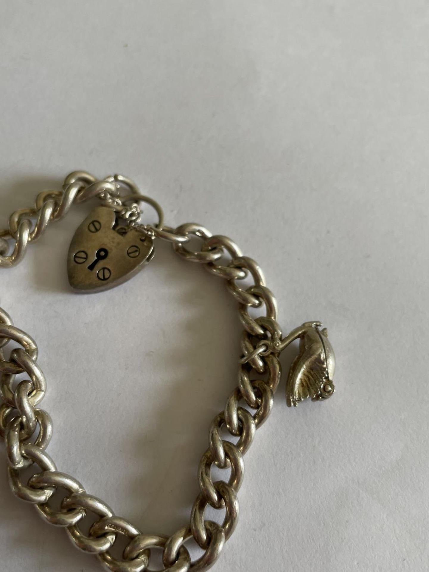 A HEAVY SILVER BRACELET WITH TWO CHARMS AND A HEART SHAPED PADLOCK - Image 3 of 3