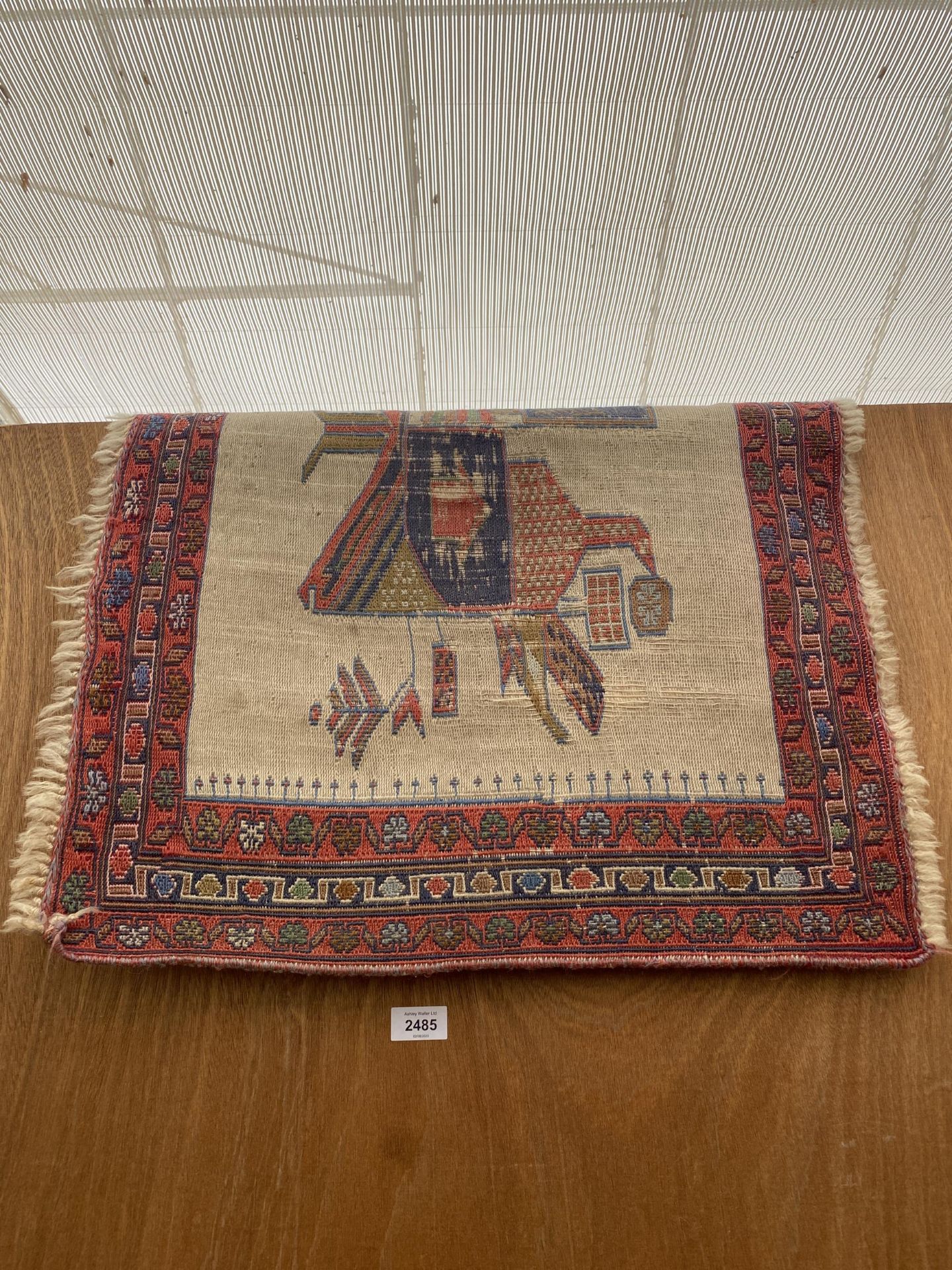 A SMALL RED PATTERNED FRINGED RUG
