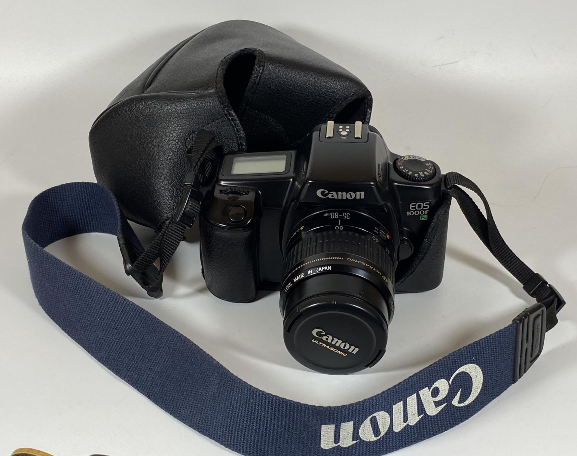 A CANON EOS 1000F N CAMERA FITTED WITH CANON ZOOM 35-80MM LENS AND CANON STRAP AND BAG