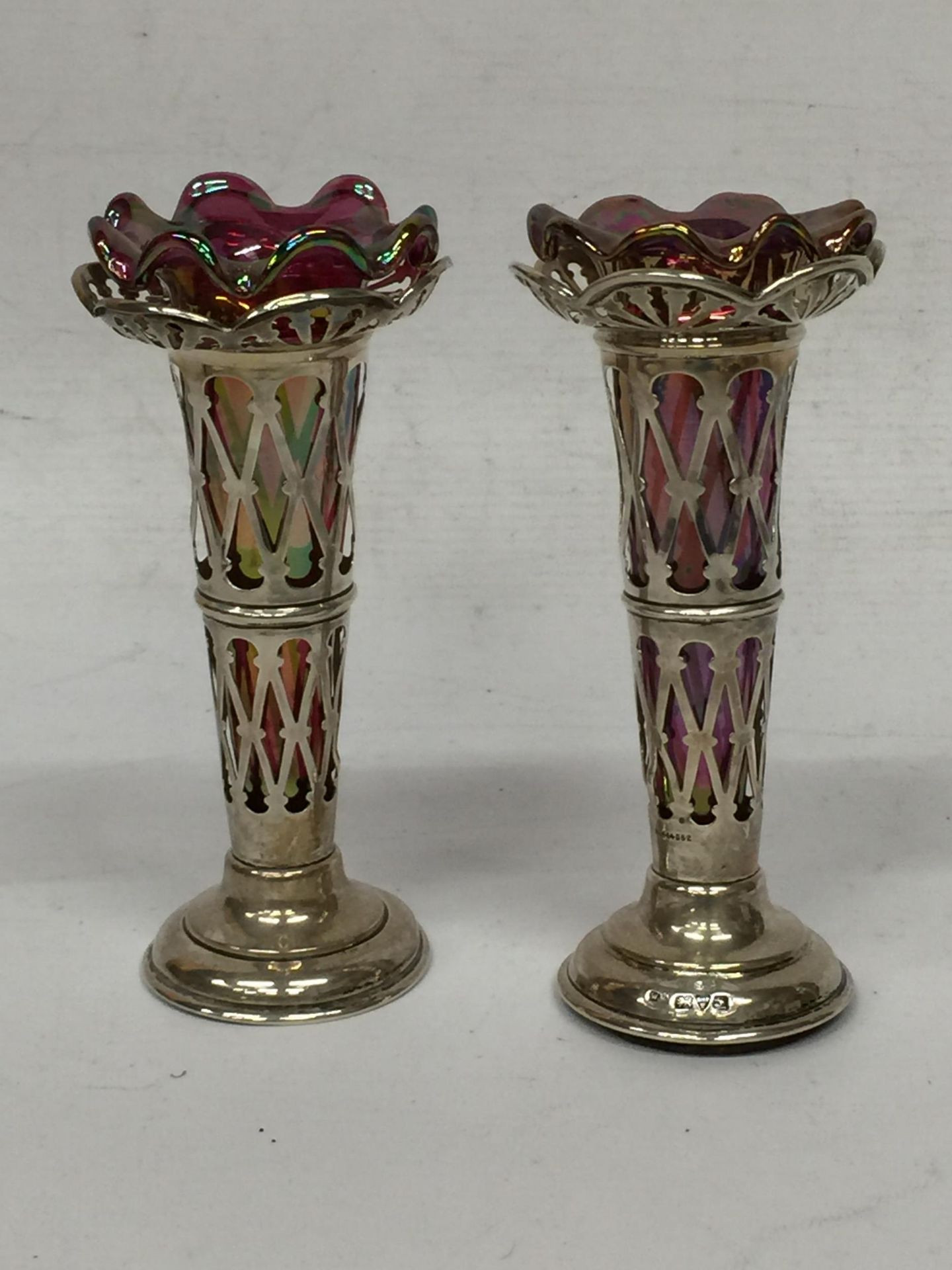 A PAIR OF CHESTER HALLMARKED SILVER BUD VASES WITH PINK LUSTRE EFFECT GLASS LINERS