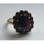 A 9CT YELLOW GOLD AND GARNET RING IN A FLOWER DESIGN SIZE P, WEIGHT 5.46 GRAMS