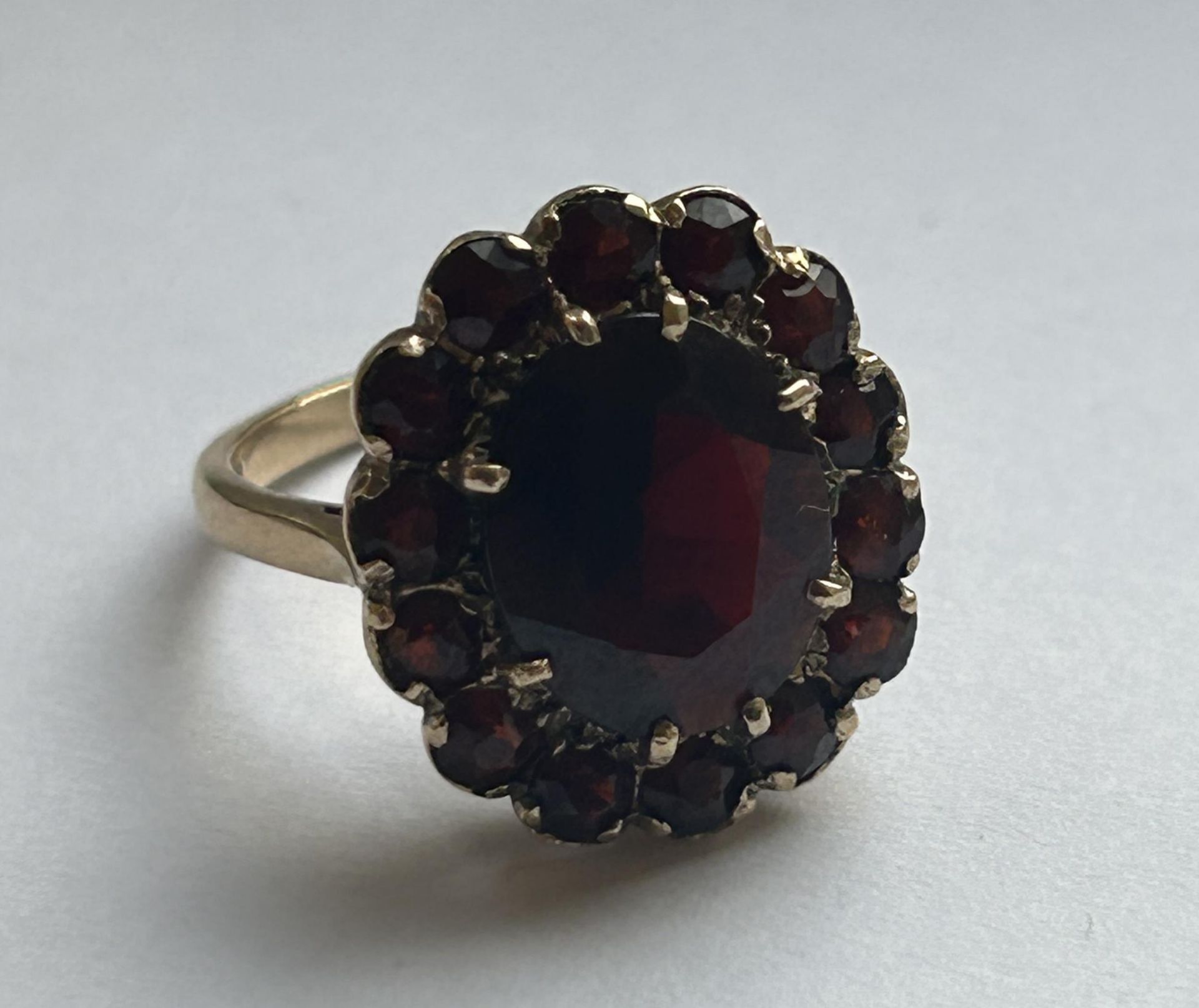 A 9CT YELLOW GOLD AND GARNET RING IN A FLOWER DESIGN SIZE P, WEIGHT 5.46 GRAMS