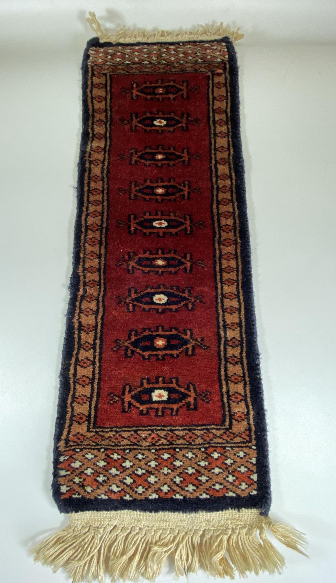 A VINTAGE MIDDLE EASTERN PERSIAN RED SAMPLE RUNNER, LENGTH 63CM
