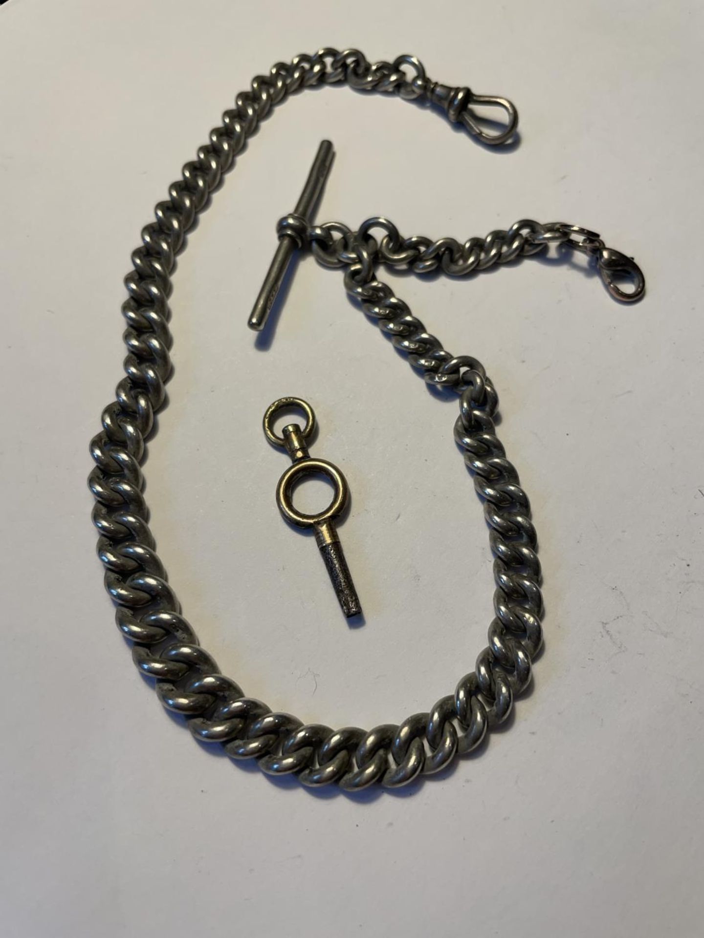 A SILVER ALBERT WATCH CHAIN WITH EACH LINK AND T BAR HALLMARKED AND A POCKET WATCH KEY