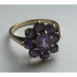 A 9CT YELLOW GOLD AND AMETHYST RING IN A FLOWER DESIGN SIZE Q, WEIGHT 3.57 GRAMS