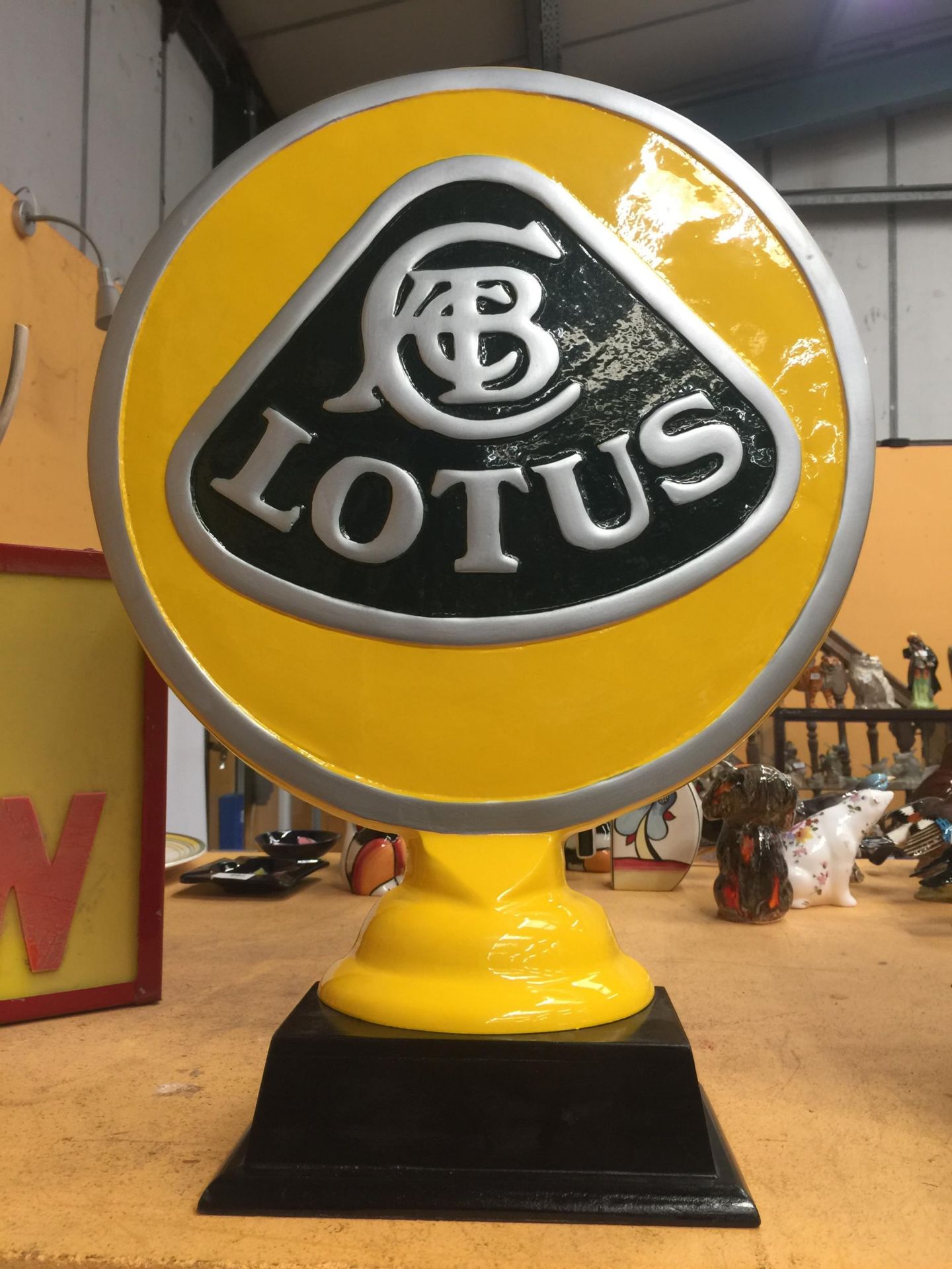 A YELLOW METAL LOTUS SIGN ON WOODEN BASE
