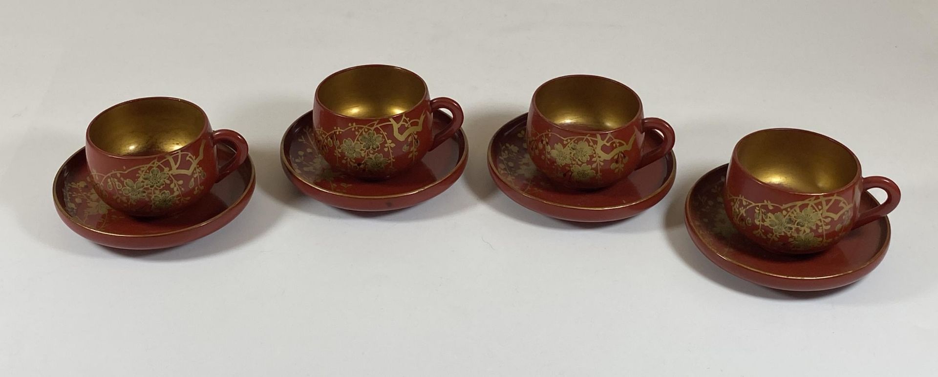 A SET OF FOUR ORIENTAL RED AND GILT LACQUERED CUPS AND SAUCERS, SAUCER DIAMETER 9.5CM