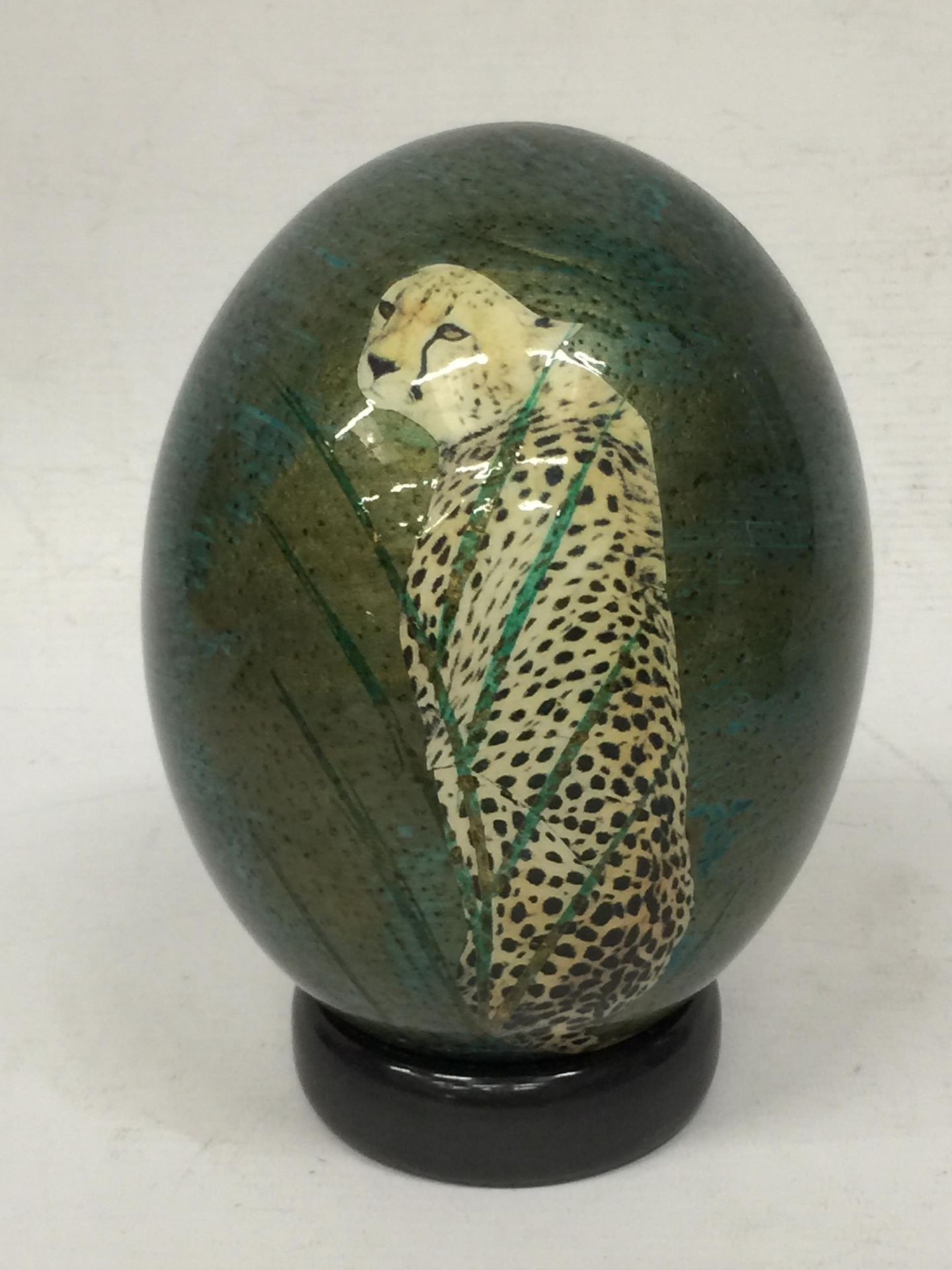 A HAND PAINTED OSTRICH EGG WITH CHEETAH DESIGN ON STAND