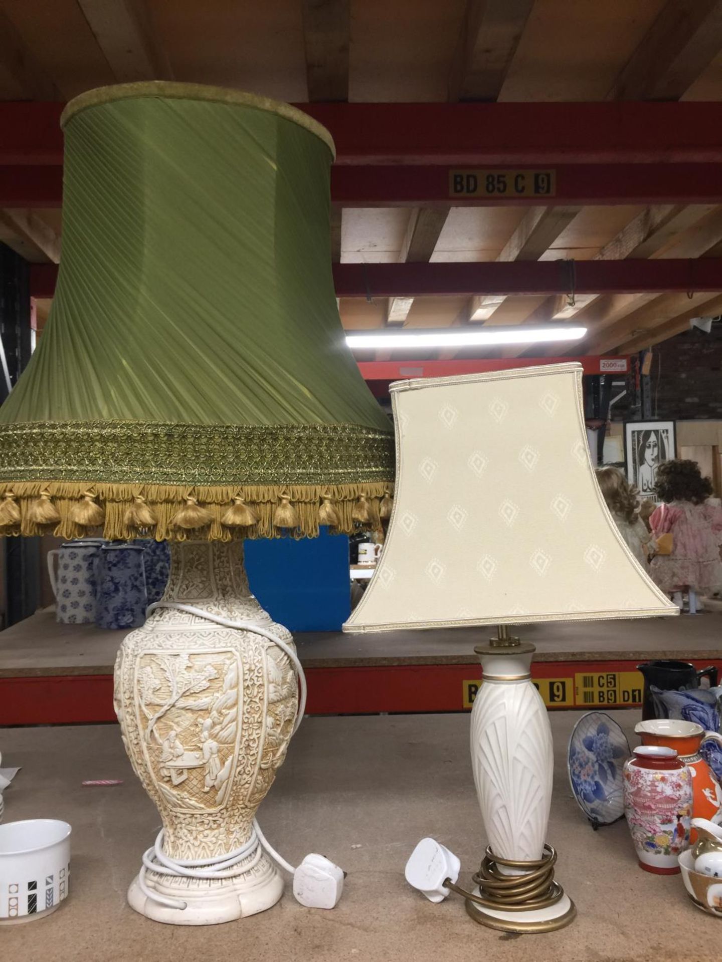A LARGE VINTAGE WHITE RESIN TABLE LAMP WITH EMBOSSED DETAIL AND A SAGE GREEN SHADE WITH TASSLES