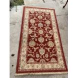 A RED PATTERNED FRINGED RUG