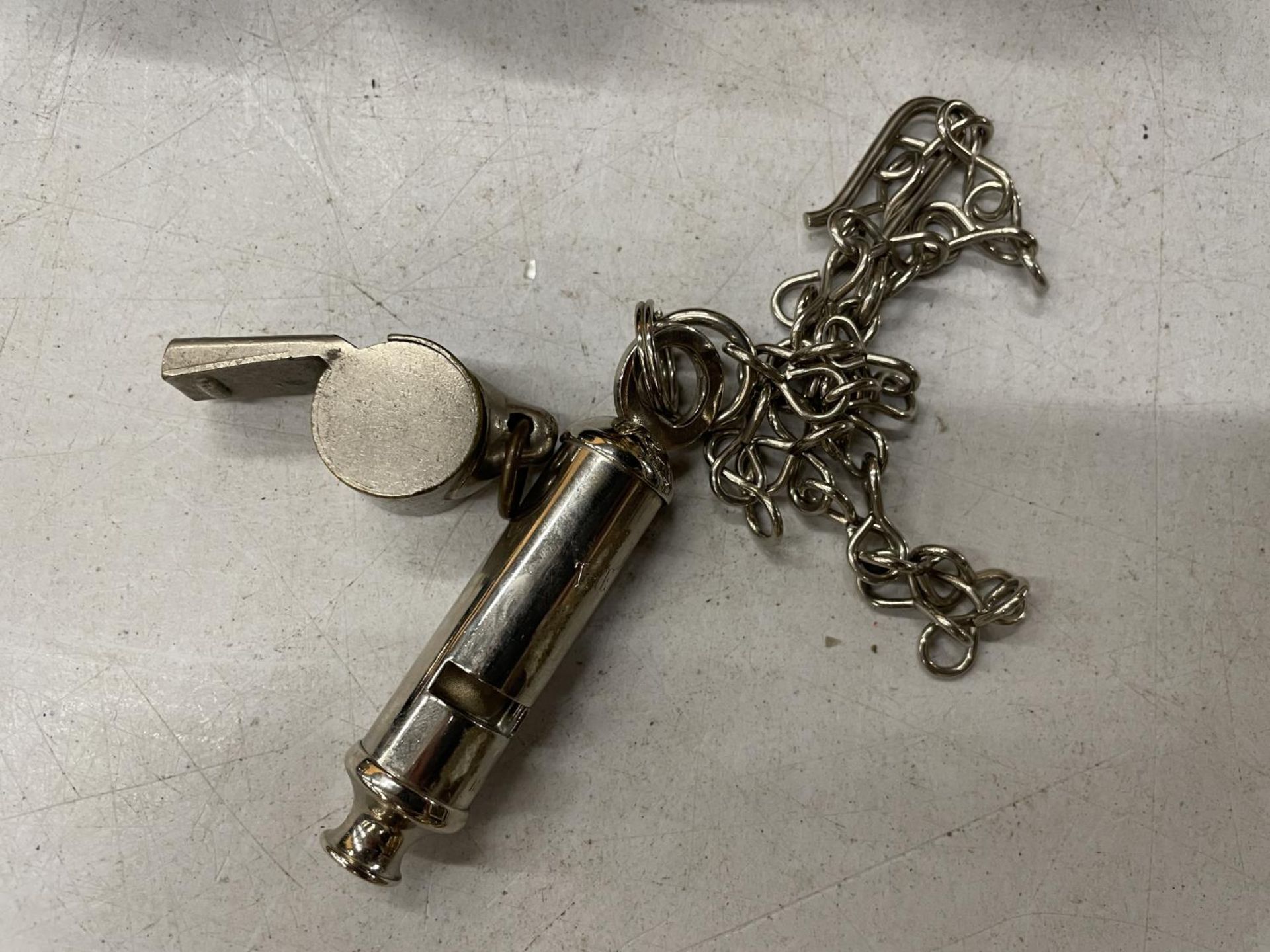 TWO VINTAGE WHISTLES TO INCLUDE 'THE METROPOLITAN' ON A CHAIN