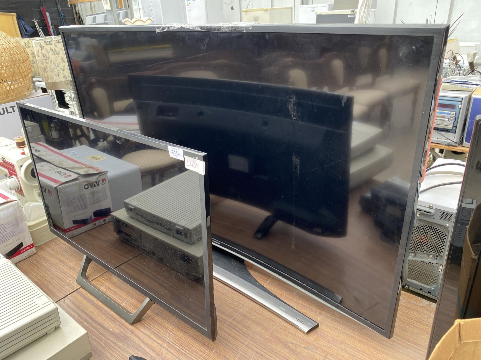 A SONY FLATSCREEN TELEVSION TOGETHER WITH LARGER CURVED SAMSUNG TELEVISION