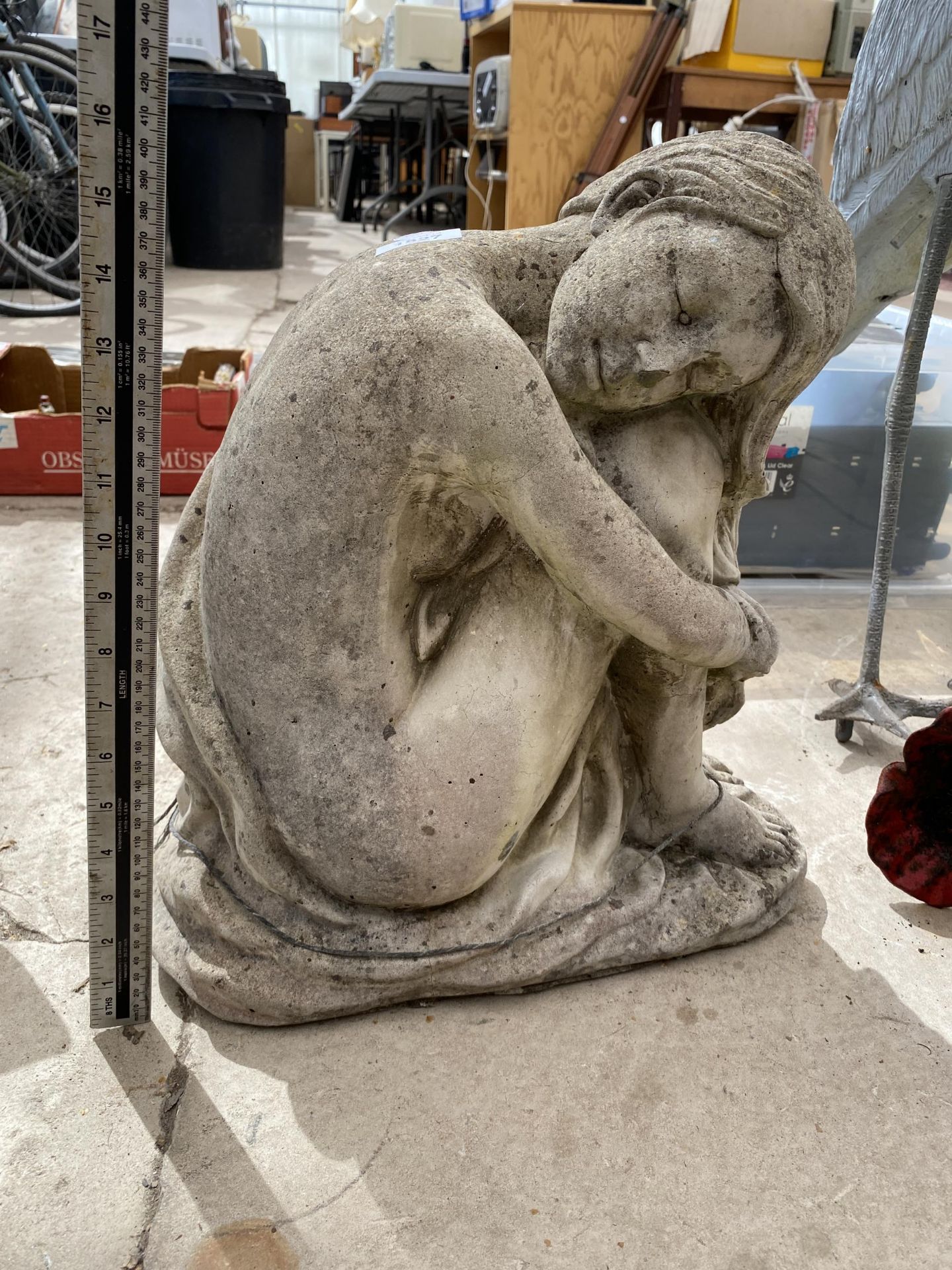 A GARDEN STONE STATUE OF A SITTING LADY