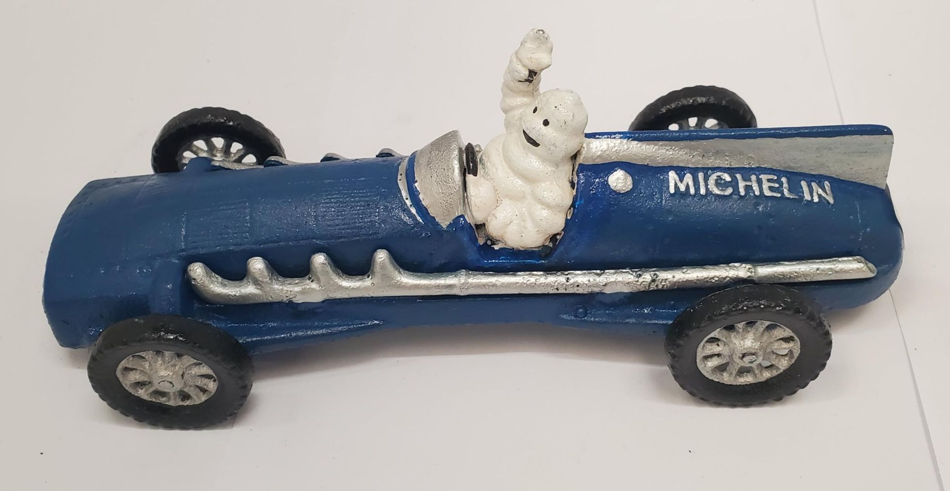 A CAST BLUE MICHELIN MAN IN A RACING CAR