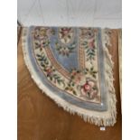 A BLUE HALF MOON PATTERNED FRINGED RUG