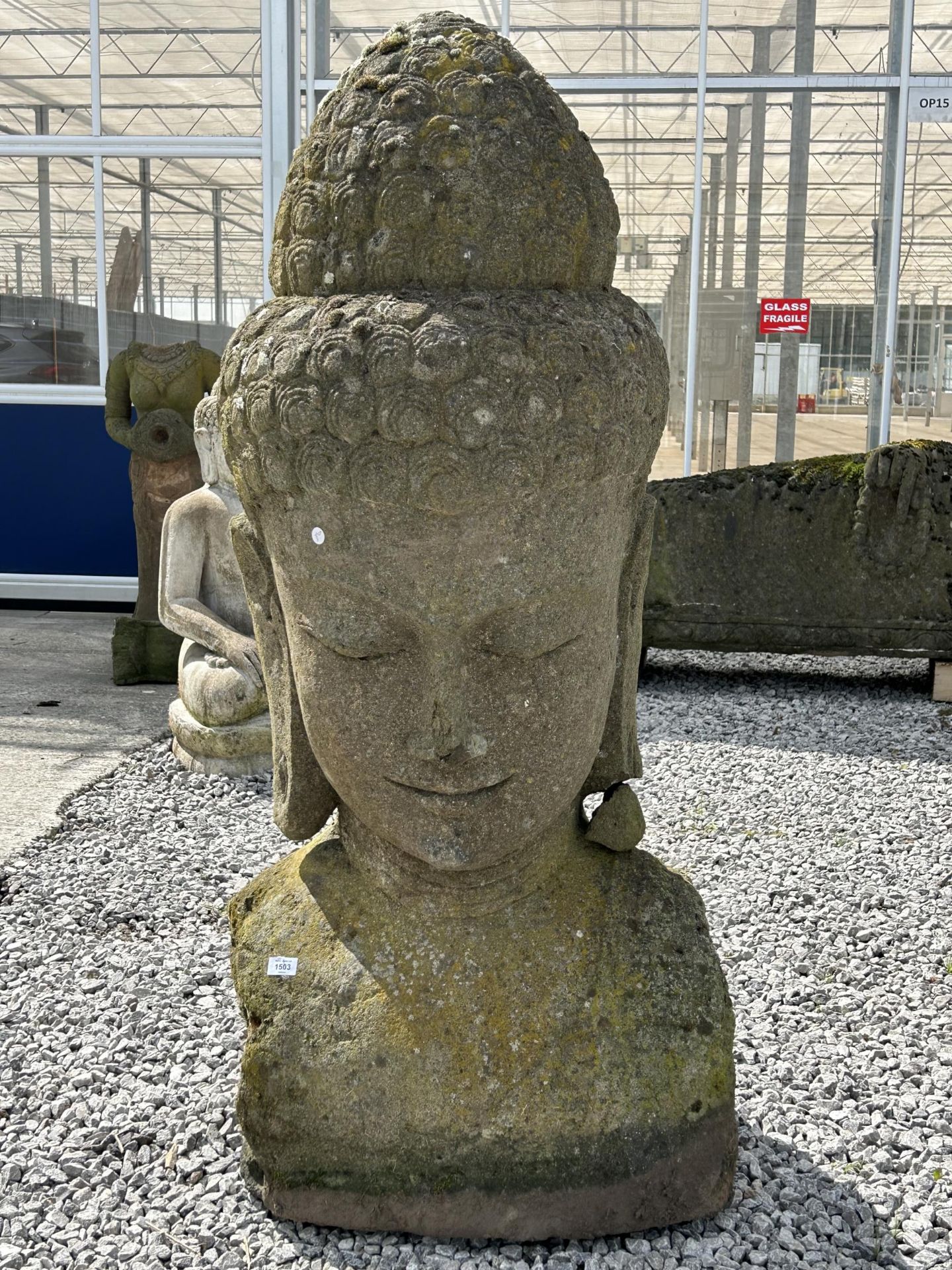 A LARGE RECONSTITUTED STONE BUDDHIST DIETY FIGURE - HEIGHT 150 CM, DEPTH 50 CM (SLIGHT A/F TO EAR