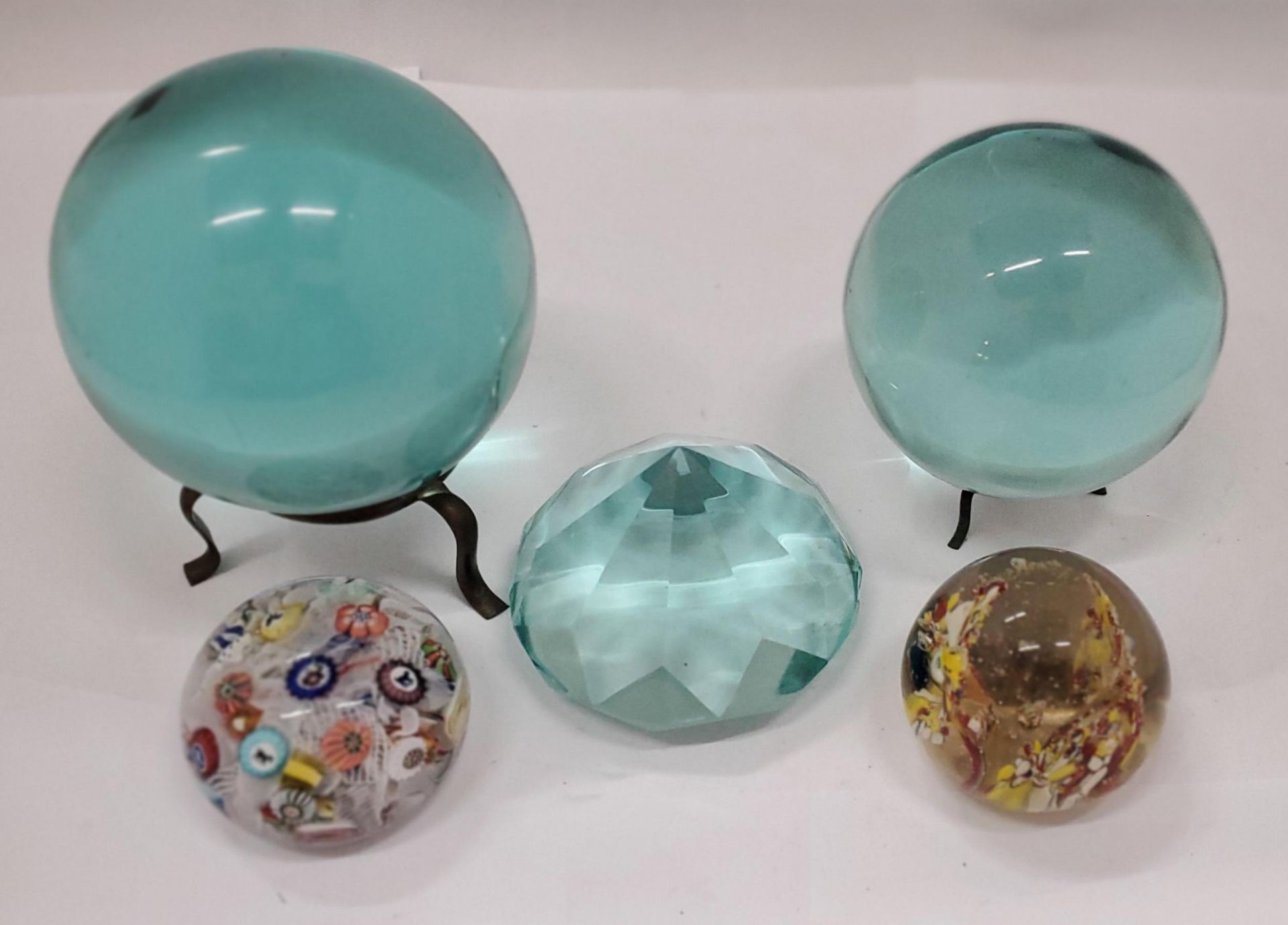 TWO TURQUOISE GLASS 'CRYSTAL BALLS' ON STANDS, A LARGE TURQUOISE CRYSTAL PLUS TWO PAPERWEIGHTS