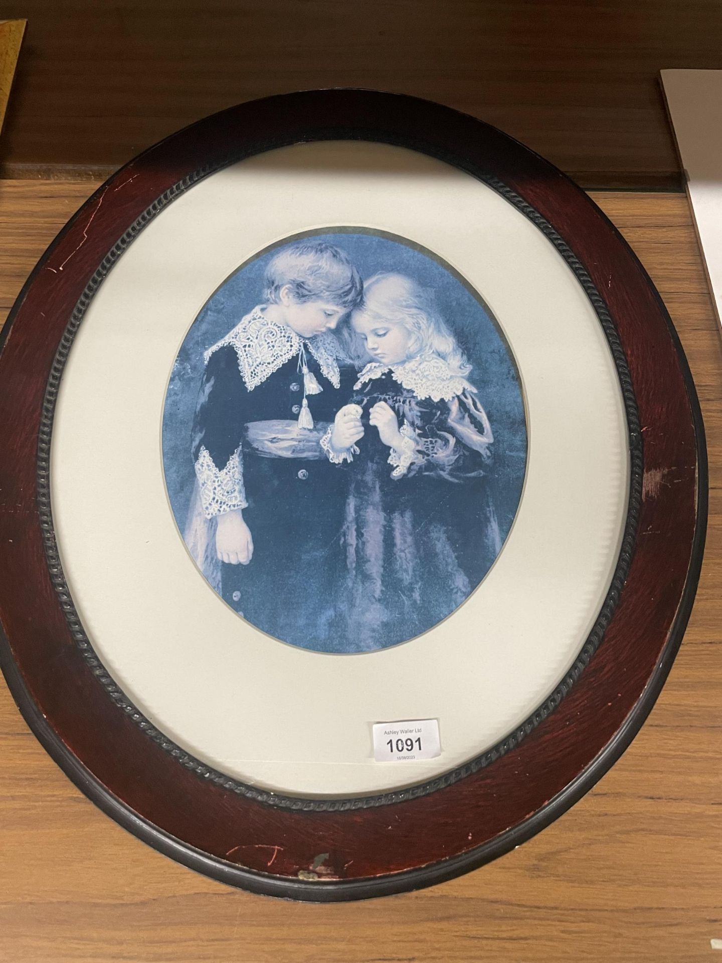 AN OVAL FRAMED PRINT OF A BOY AND GIRL