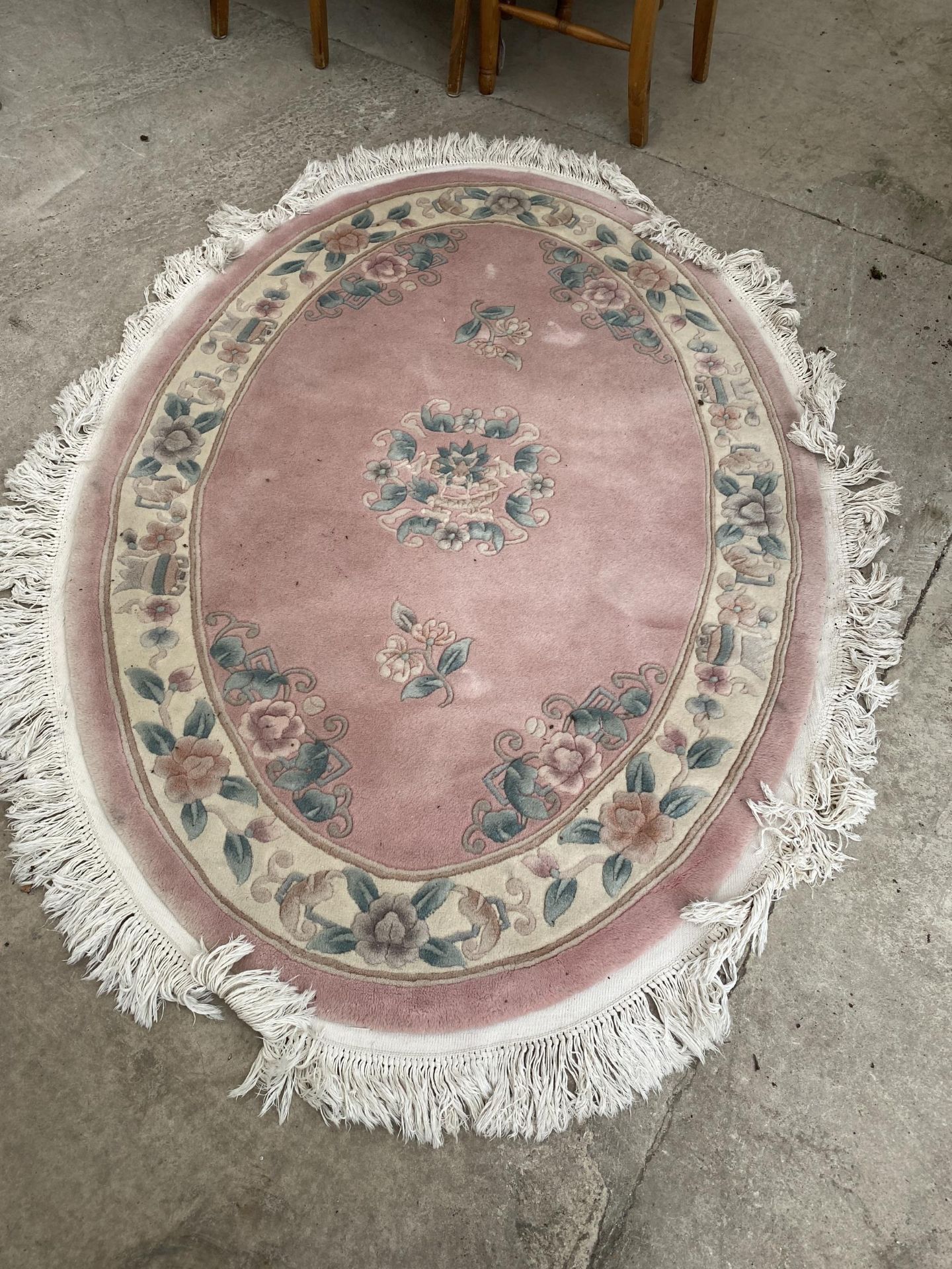 AN OVAL SALMON PATTERNED FRINGED RUG