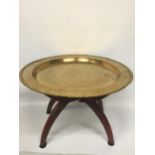 A VINTAGE MIDDLE EASTERN DESIGN BRASS TRAY ON WOODEN STAND