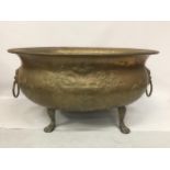 A LARGE BRASS BOWL ON PAW FEET WITH FIGURAL HANDLES