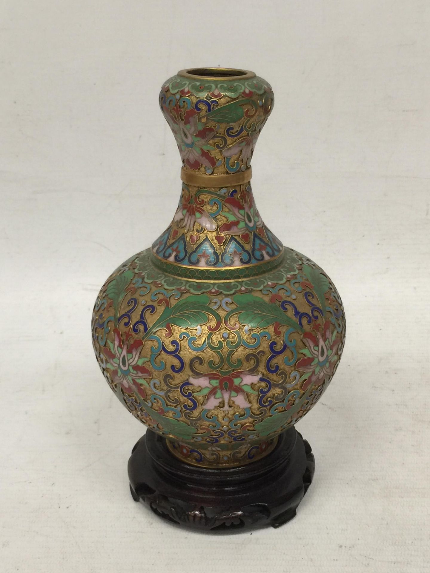 A VINTAGE ORIENTAL CLOISONNE BOTTLE SHAPED VASE ON WOODEN STAND