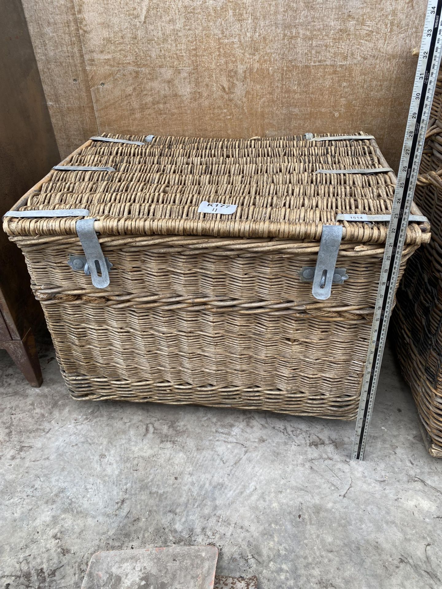 A LARGE WICKER LOG BASKET WITH HINGED LID AND METAL BANDING