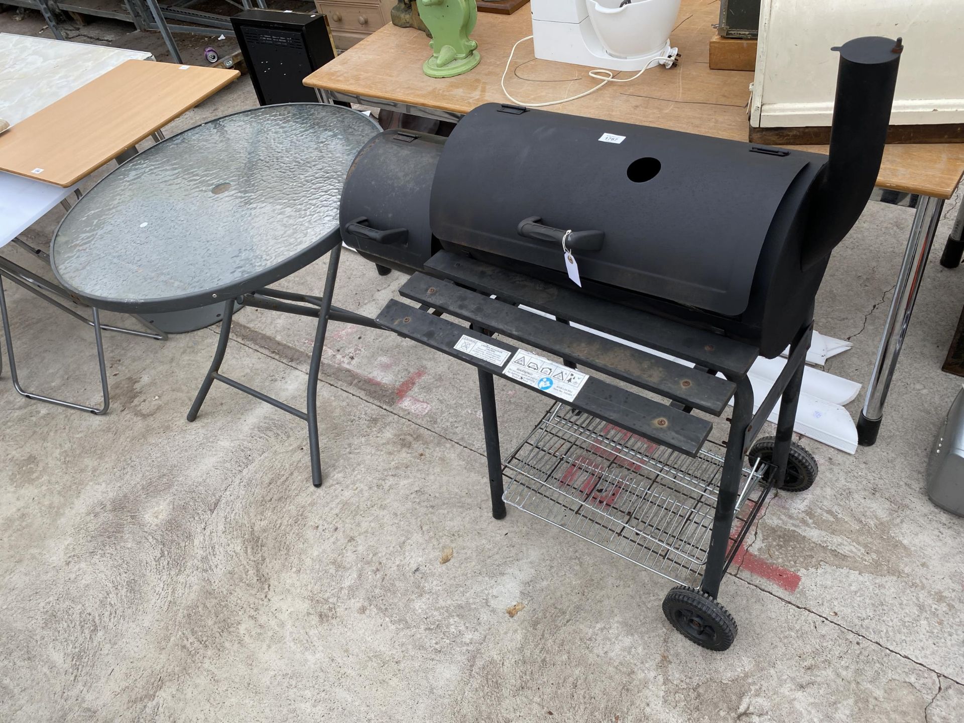 A CHARCOAL BBQ AND A GLASS TOPPED PATIO TABLE