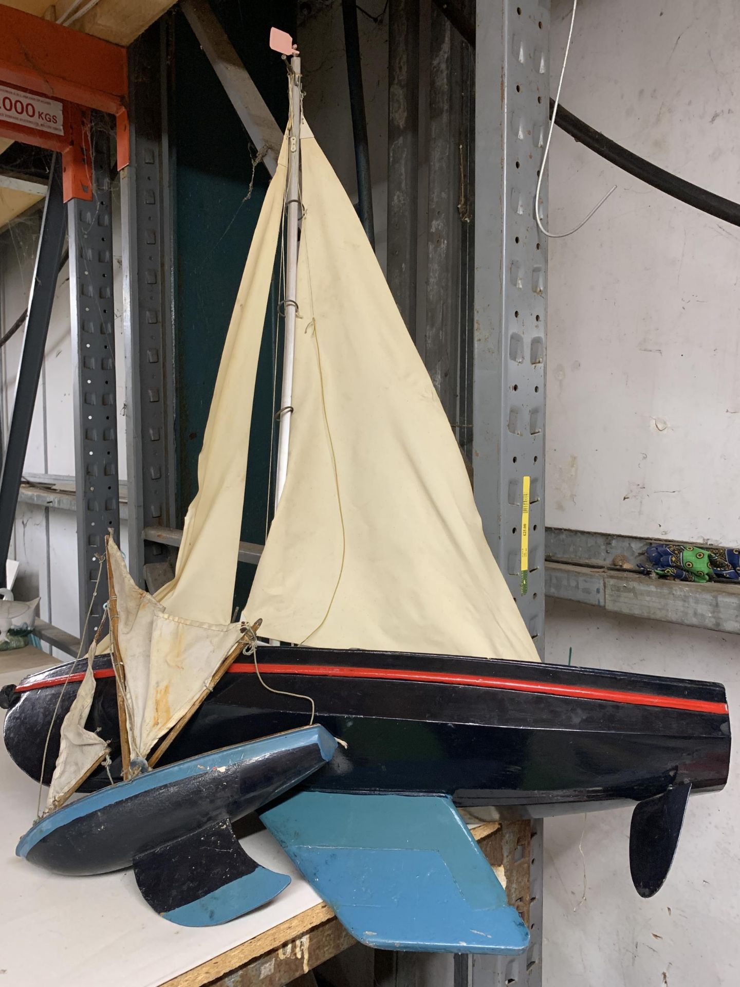 A WOODEN SAIL BOAT MODEL WITH CLOTH SAILS AND ANOTHER SMALLER