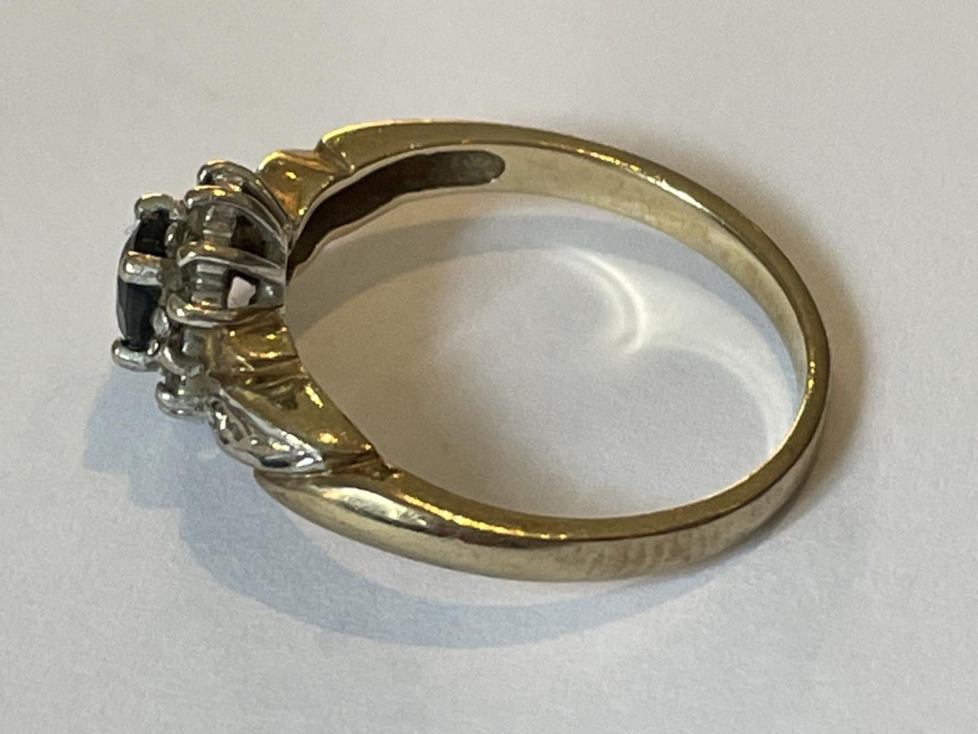 A 9 CARAT GOLD RING WITH A CENTRE SAPPHIRE SURROUNDED BY DIAMONDS SIZE O - Image 2 of 3