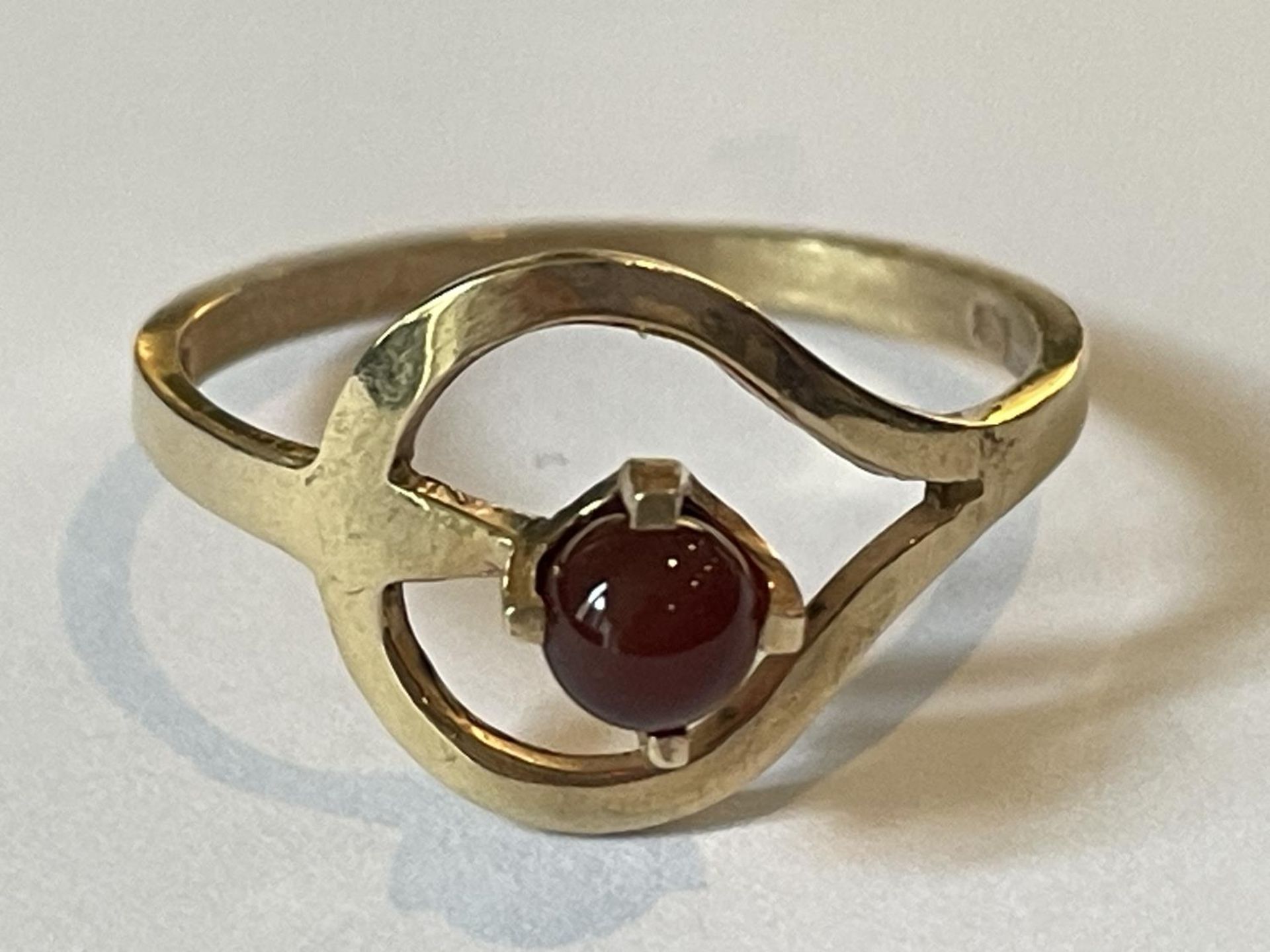 A 9 CARAT GOLD RING WITH A SPHERICAL GARNET IN A HEART SETTING SIZE O