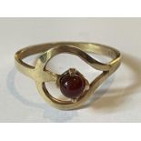 A 9 CARAT GOLD RING WITH A SPHERICAL GARNET IN A HEART SETTING SIZE O