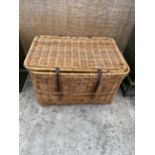 A LARGE WICKER LOG BASKET WITH HINGED LID AND LEATHER STRAPPING