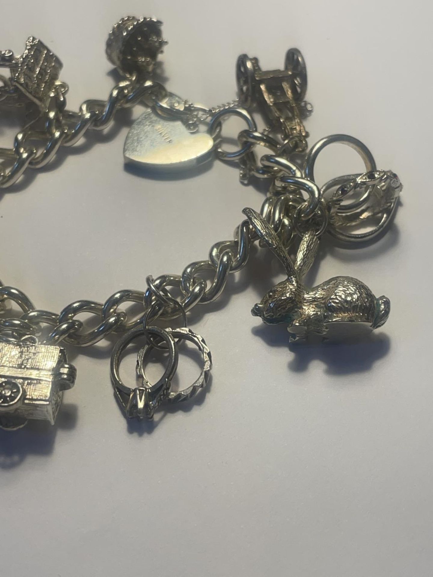 A SILVER CHARM BRACELET WITH ELEVEN CHARMS AND A HEART LOCK - Image 4 of 4