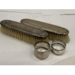 FOUR HALLMARKED SILVER ITEMS - TWO BRUSHES AND TWO NAPKIN RINGS