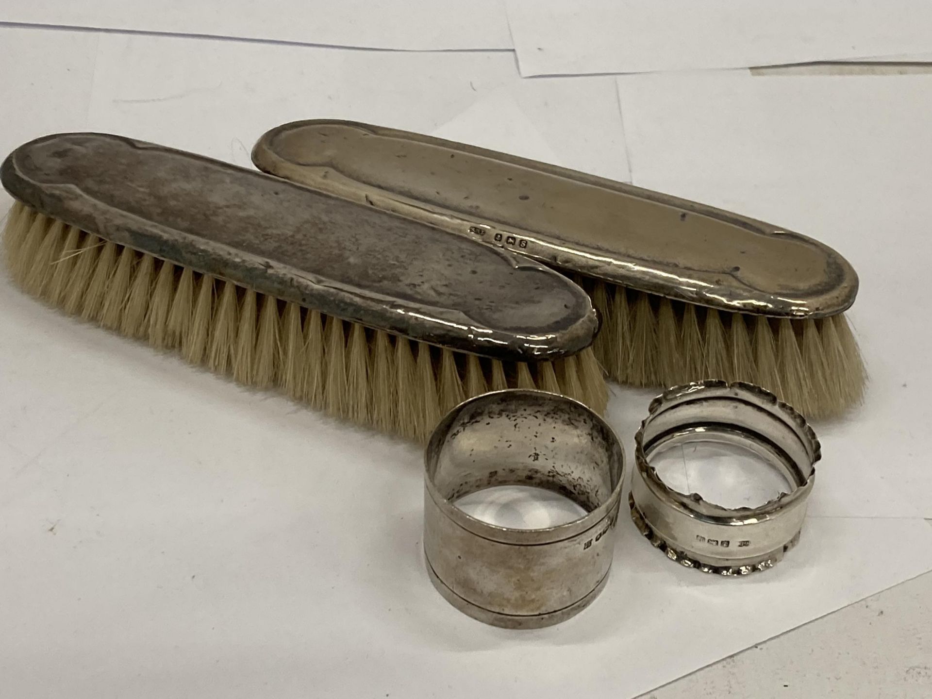 FOUR HALLMARKED SILVER ITEMS - TWO BRUSHES AND TWO NAPKIN RINGS