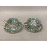 A PAIR OF CONTINENTAL PORCELAIN TURQUOISE AND GILT DESIGN CUPS AND SAUCERS