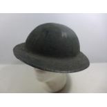 A BRITISH ARMY EARLY TO MID 20TH CENTURY GREEN PAINTED STEEL HELMET WITH LEATHER LINING