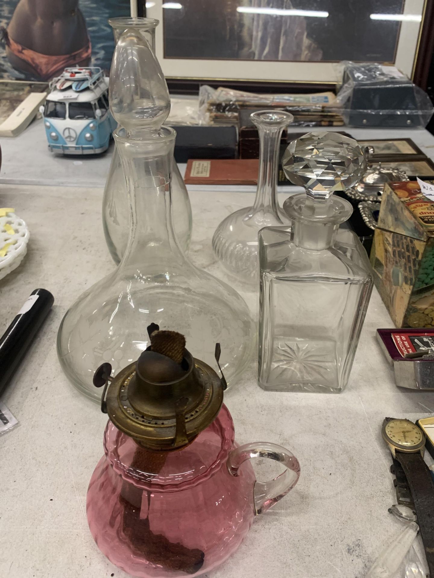 A GROUP OF VINTAGE DECANTERS AND A CRANBERRY GLASS CONVERTED OIL LAMP JUG