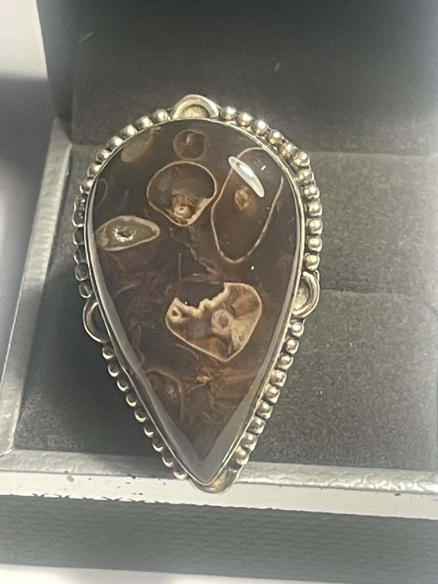 A SILVER RING WITH A FOSSIL STONE IN A PRESENTATION BOX