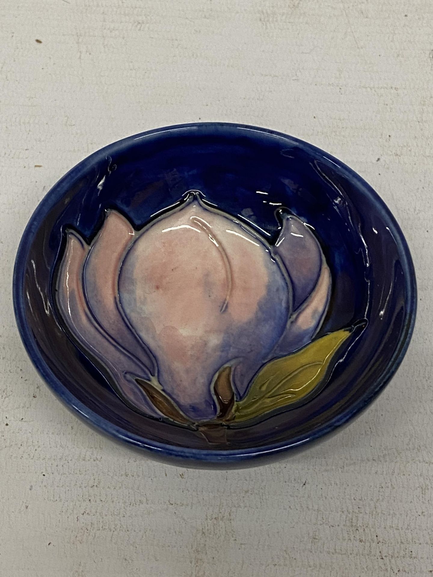 A MOORCROFT PINK MAGNOLIA PATTERN SMALL BOWL ON BLUE GROUND