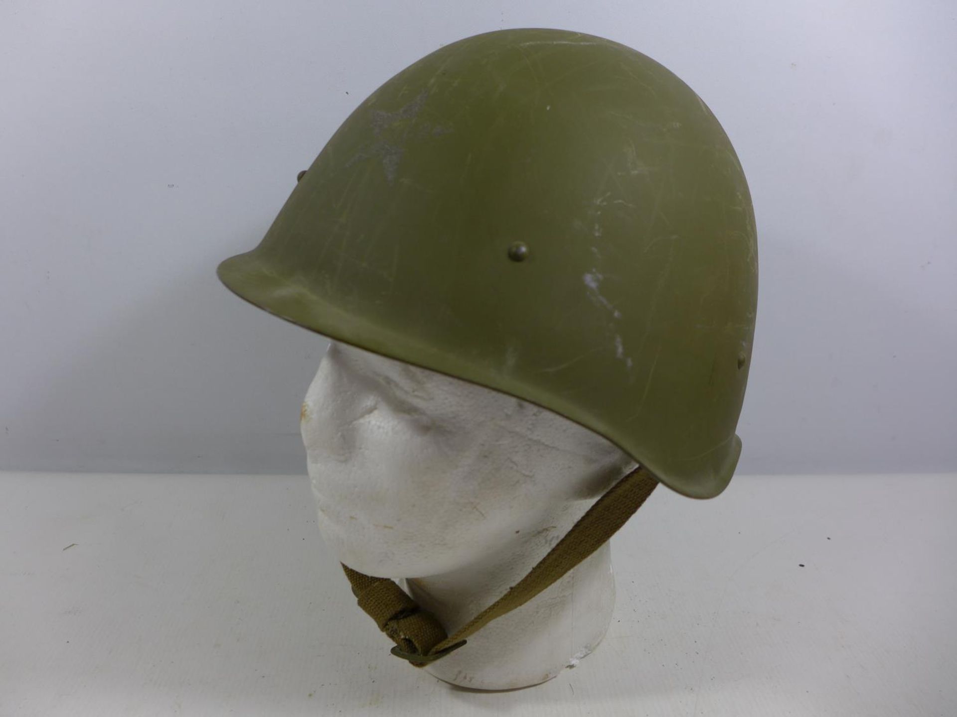 A GREEN PAINTED MILITARY HELMET WITH LEATHER LINING