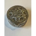 A SILVER CIRCULAR PILL BOX WITH FLORAL DECORATION
